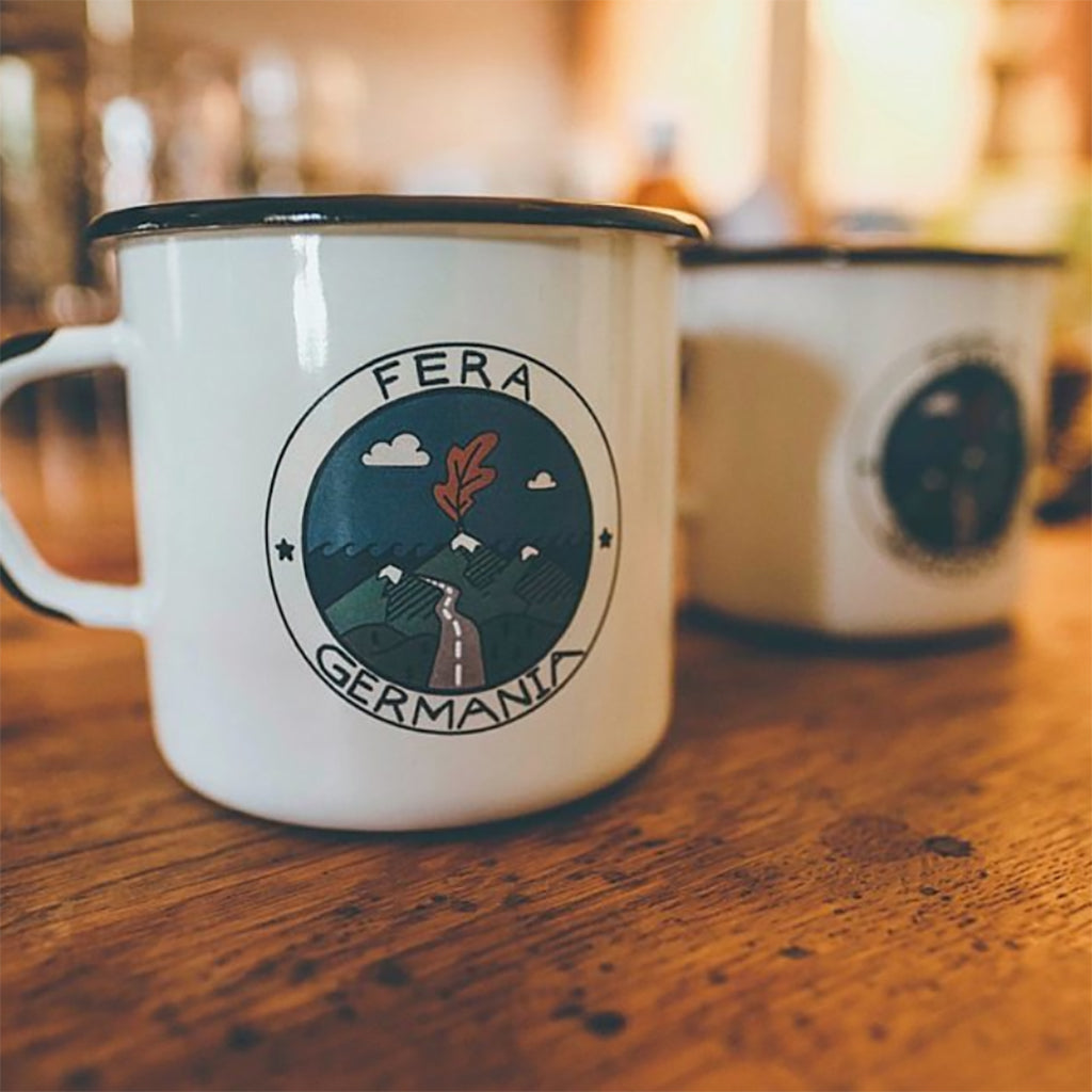 White mug with 'Fera Germania' logo on a wooden table